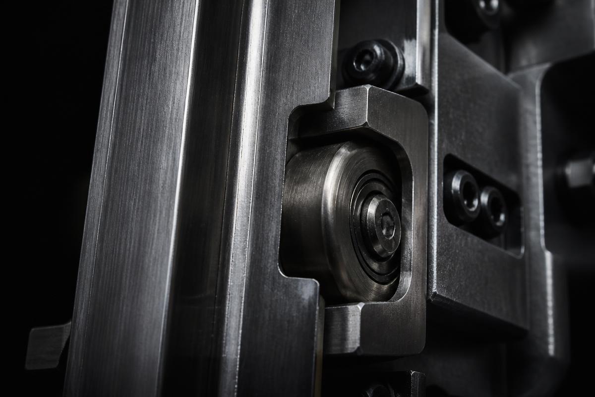 Close-up of a machined steel elevator guide rail and roller assembly
