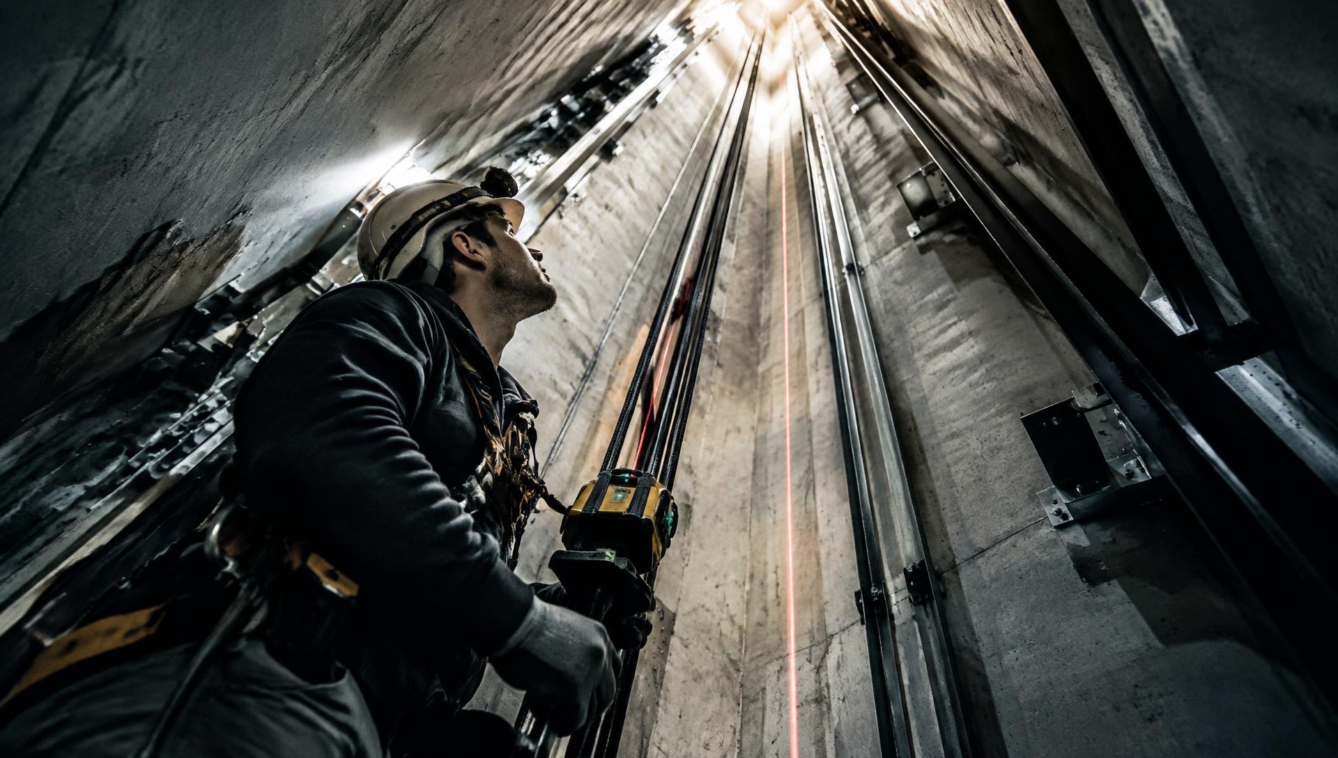 Rudrax technician aligning elevator guide rails inside a shaft with a laser level